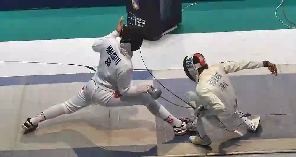 L'immagine mostra un intenso incontro di scherma tra uno svizzero e un francese. Entrambi gli atleti sono in azione, pieni di concentrazione e tensione. Lo svizzero attacca, il francese si difende. L'atmosfera è piena di dinamismo e determinazione.