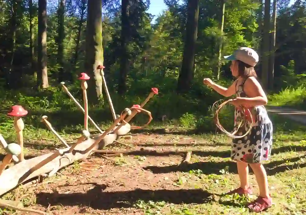 Das Bild zeigt ein Mädchen, das auf dem Elfen- und Wichtelweg in Wolfwil spielt, einer speziell gestalteten Route, die darauf abzielt, die Fantasie der Kinder anzuregen und sie in eine märchenhafte Welt zu entführen.