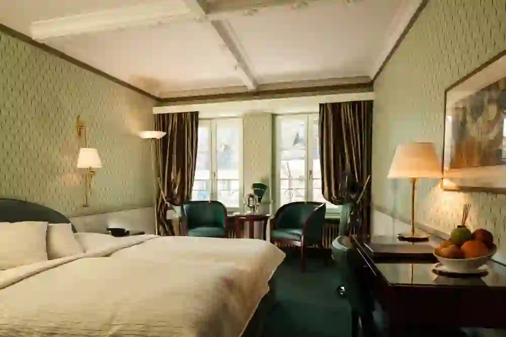 The picture shows a classically furnished hotel room in the Hotel Belle Epoque with elegant fabrics and discreet lighting, creating an atmosphere of comfort and traditional luxury for a relaxing stay.
