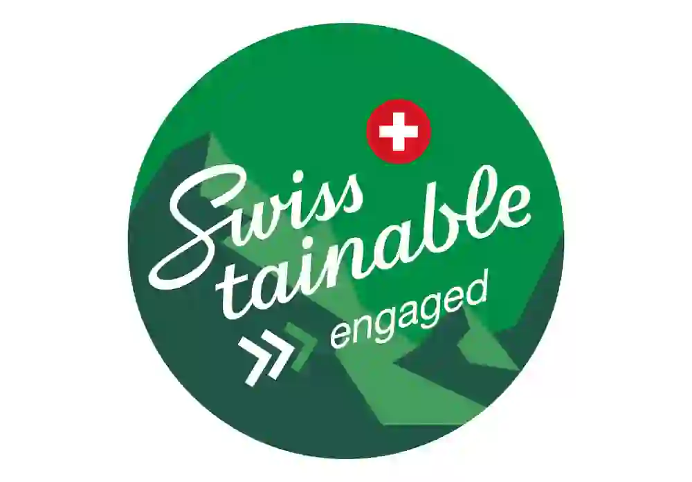 Le logo "Swisstainable engaged" montre un engagement engagé en faveur de la durabilité avec un fond vert frais et vivant représentant des montagnes et une croix suisse qui représente le pays.