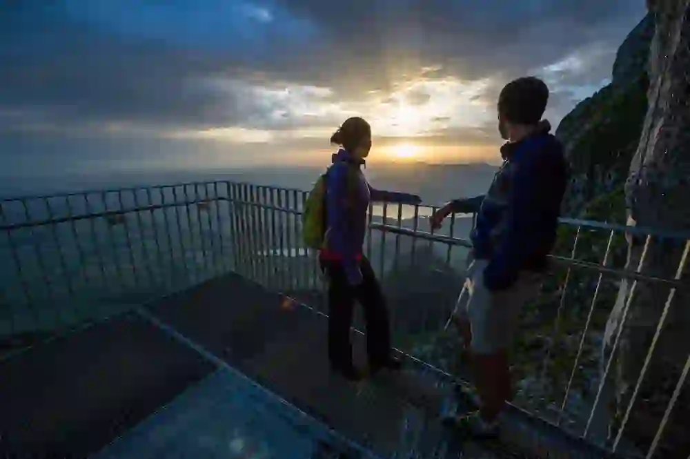 Zwei Personen stehen auf einer Aussichtsplattform am Stockhorn, verzaubert vom faszinierenden Sonnenuntergang, der den Himmel in warme Farben taucht.
