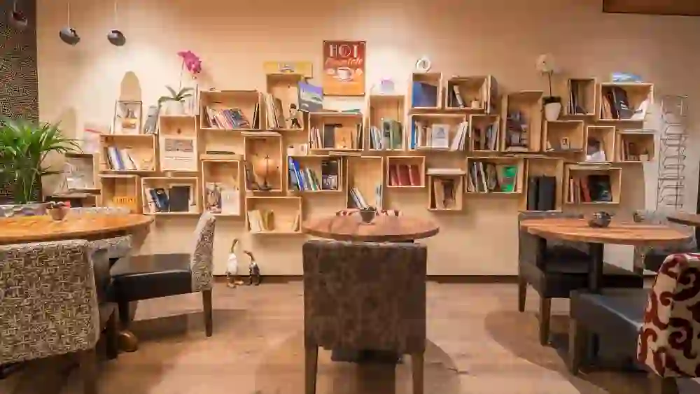 Das Bild zeigt eine behagliche Ecke der Lobby im Hotel Bären am Bundesplatz, die mit Bücherregalen und bequemen Sitzgelegenheiten eine warme, einladende und heimische Atmosphäre ausstrahlt.