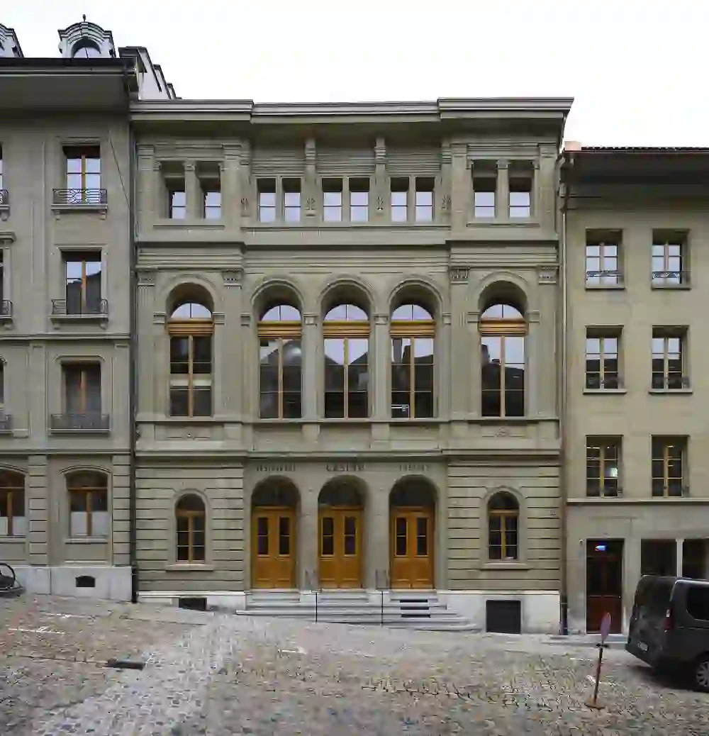 L'immagine mostra la facciata di un edificio dall'architettura classica. Le grandi finestre, gli elementi di design simmetrici e i dettagli decorativi della facciata sono sorprendenti. La facciata emana eleganza e fascino storico.