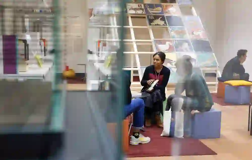 L'image montre des personnes assises et discutant de manière détendue dans un musée moderne. L'atmosphère est calme et réfléchie, entourée d'art et d'éducation, ce qui offre une toile de fond pour l'échange intellectuel et la réflexion personnelle.