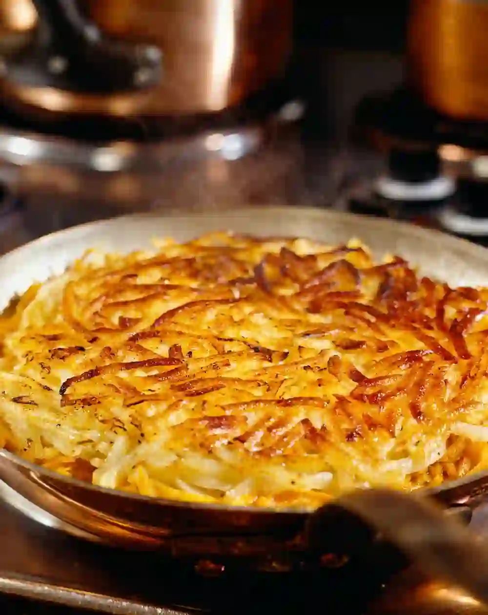 The picture shows an appetising Rösti, a traditional Swiss dish that is often served as a side dish. Rösti consists mainly of grated and fried potatoes, which are formed into a crispy, golden crust.