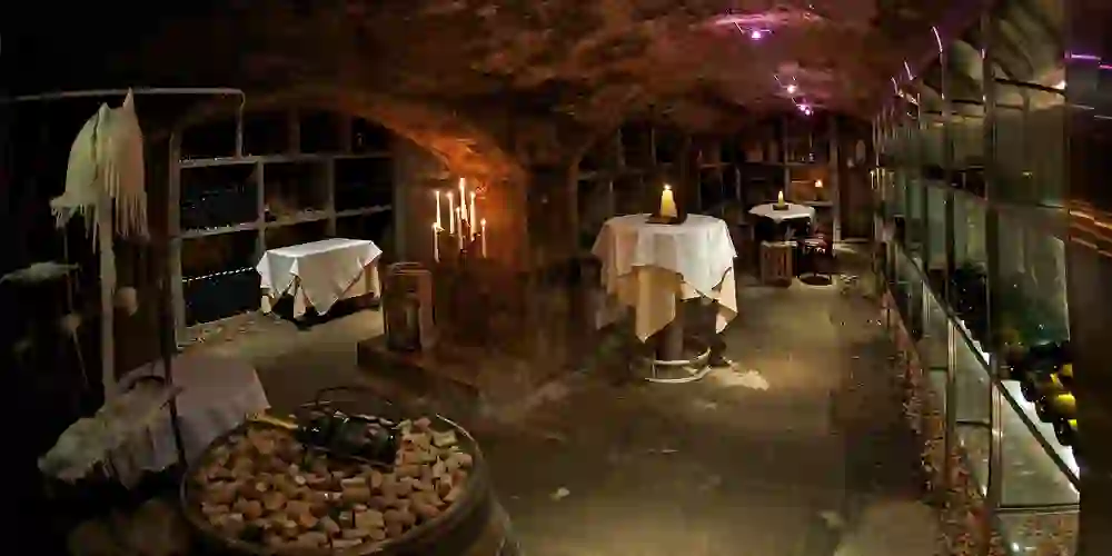 Eine Weinbar in einem historischen Gewölbekeller, beleuchtet von Kerzenlicht, erzeugt eine geheimnisvolle und zugleich behagliche Atmosphäre.