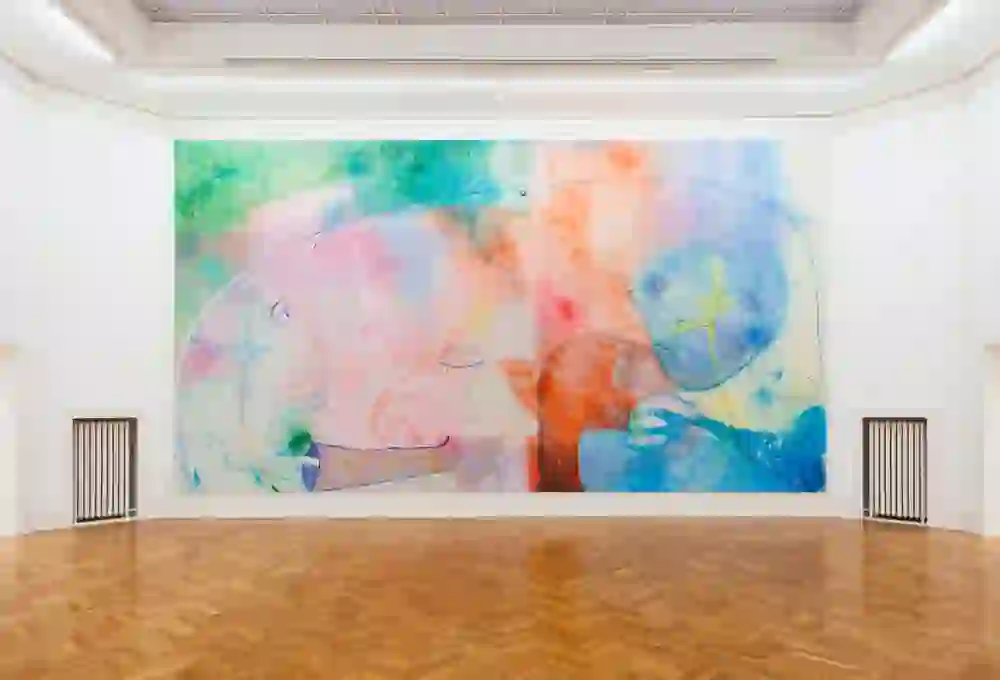 The picture shows a large, colourful mural in a spacious gallery, creating a lively and inspiring atmosphere surrounded by the elegance of classical architecture.