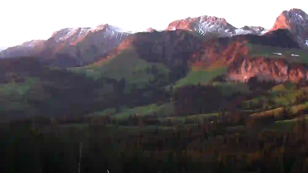 Les premiers rayons de soleil du jour plongent les sommets et les forêts du parc naturel de Gantrisch dans une lumière chaude et dorée, promesse de calme et d'éveil de la nature.