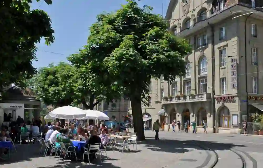 L'image montre l'Hôtel National classique de l'extérieur avec des arbres au premier plan, ce qui donne une atmosphère détendue et conviviale.