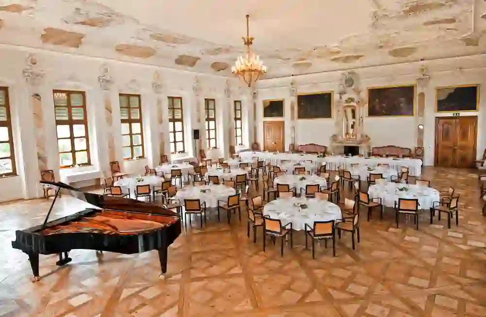 Eleganter Festsaal mit gedeckten Rundtischen und Flügel. Das Ambiente ist festlich und edel, geprägt von Vorfreude auf besondere Momente.