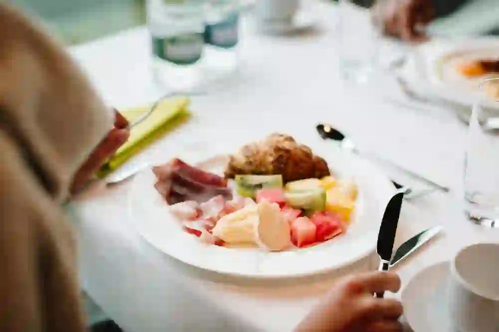 Une assiette de brunch appétissante crée une atmosphère agréable et conviviale. Les fruits frais, le fromage et la charcuterie invitent à la dégustation, tandis qu'en arrière-plan, la conversation et le tintement des couverts soulignent le sentiment d'une matinée détendue au pavillon du Gurten.