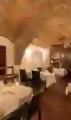 The photo shows the restaurant Wein und Sein in Bern with its rustic charm, which is housed in a vaulted room. The red bricks of the ceiling, the warm wall lights and the carefully laid tables with white tablecloths create a cosy and warm atmosphere. The ambience combines historical architecture with modern comfort, promising an inviting place for an intimate dinner.