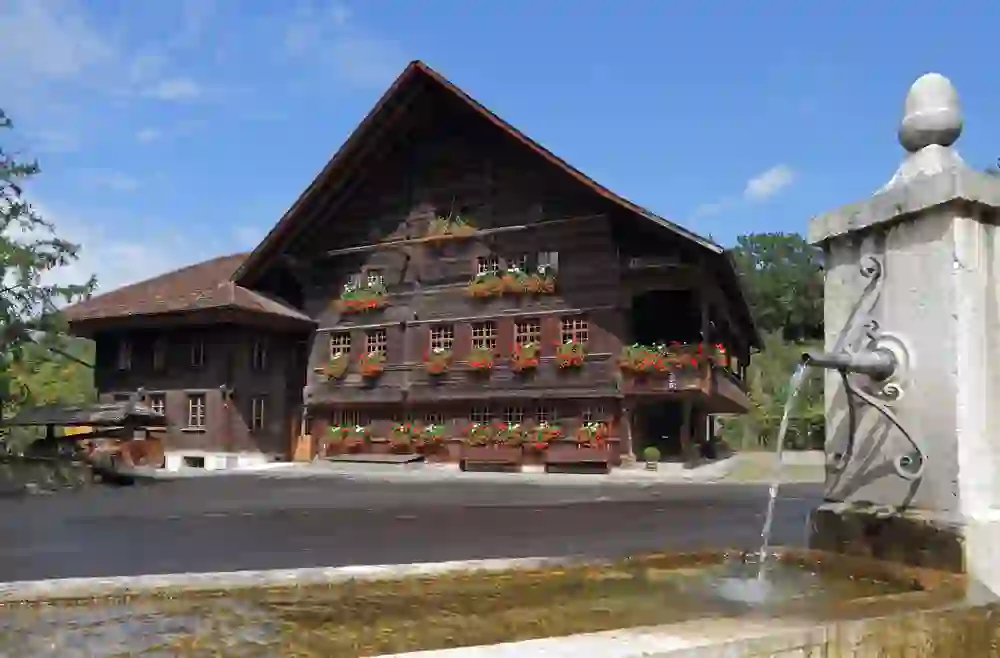 Voici une charmante image du musée régional Chüechlihus à Langnau, qui présente l'architecture traditionnelle suisse. La structure en bois est très pittoresque, avec sa couleur riche et profonde et ses balcons caractéristiques, ornés de fleurs d'un rouge vif.