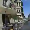 Café de rue ensoleillé dans une ruelle animée, avec des clients sous des parasols qui profitent de l'ambiance détendue de l'architecture historique.