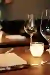 L'immagine mostra un tavolo apparecchiato al ristorante Bonbec di Berna, dove la calda luce delle candele crea un'atmosfera accogliente e invitante per un'esperienza culinaria intima.