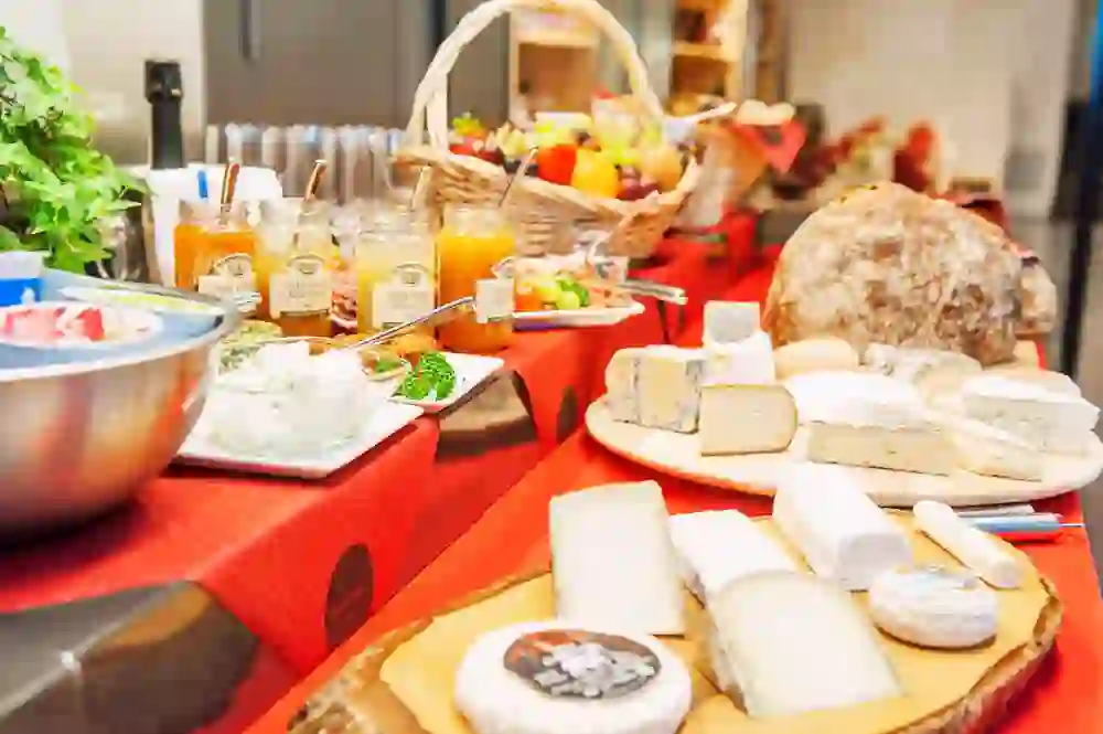 L'image présente un appétissant buffet de brunch au Chäsbueb avec une multitude de fromages, du pain rustique, des fruits frais et diverses pâtes à tartiner, le tout dans une atmosphère chaleureuse et savoureuse.