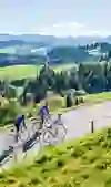 Road cyclists climb a hill on a route near Lueg, surrounded by the breathtaking views of the Emmental. The effort and ambition are reflected in their posture, while the clear air and panorama promise strength and relaxation.