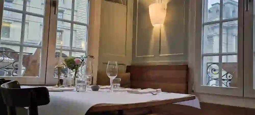 Un tavolo elegante proprio accanto alla finestra, con vista su Kornhausplatz. Il lume di candela e i fiori freschi creano un'atmosfera accogliente ed elegante all'interno del ristorante.