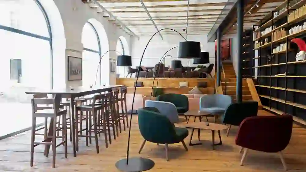 Ein einladendes Café mit gemütlich-moderner Einrichtung, warmen Holztönen und stilvollen Sitzbereichen, strahlt Ruhe und eine entspannte Atmosphäre aus.