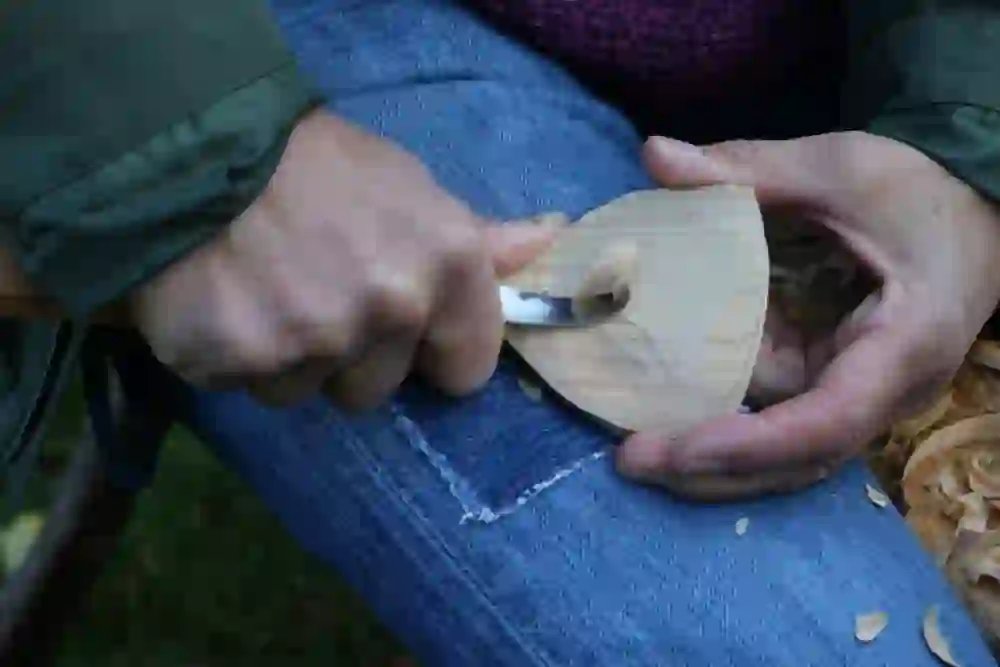 Auf dem Bild sieht man eine Person welche mit ein Holzbrett schnitzt