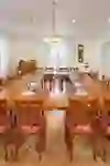 Bright, classically furnished room with a large wooden table, elegant chairs, plenty of natural light and decorative elements. Ideal for small meetings or private gatherings in a stylish atmosphere.