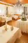 Intérieur élégant du restaurant avec des nappes blanches, des chaises en bois et un éclairage doux. Des poissons décoratifs sur les murs et une table centrale avec des plantes.