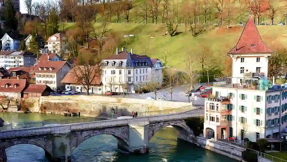 Das Bild zeigt die malerische Stadtansicht mit dem Landhaus by Albert & Frida, umgeben von traditionellen Gebäuden und einer grünen Hügellandschaft im Hintergrund.