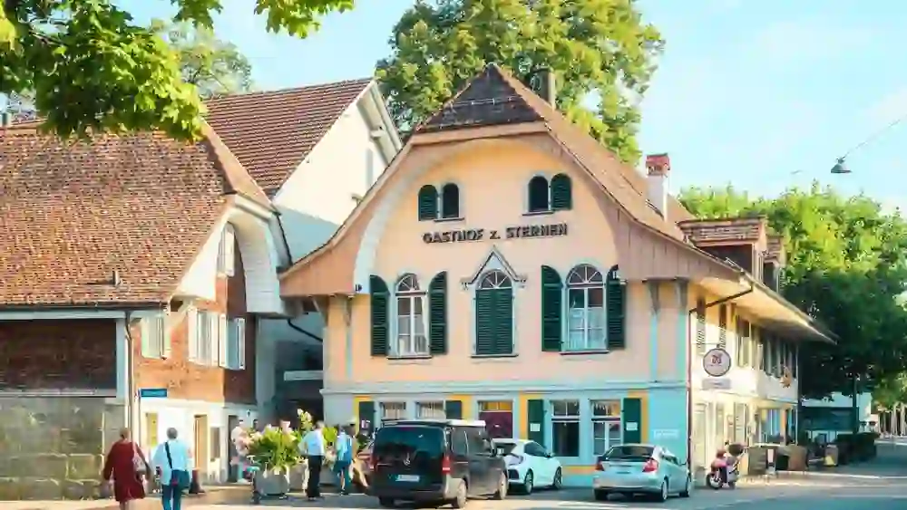 Das Gasthaus zum Sternen in Bümpliz strahlt mit seiner charmanten, historischen Fassade und den typischen grünen Fensterläden eine einladende Atmosphäre aus. Die idyllische Lage und die liebevoll gestalteten Blumendekorationen schaffen einen einladenden und gemütlichen Eindruck. Gäste werden hier mit herzlicher Gastfreundschaft empfangen, während sie die gemütliche Umgebung und das kulinarische Angebot genießen. Ein Treffpunkt für Einheimische und Besucher, der Tradition und Moderne auf harmonische Weise verbindet.