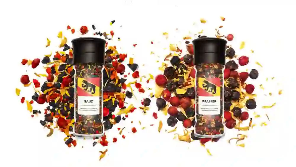 Zwei Gewürzstreuer mit einer bunten Mischung aus Pfefferkörnern und Gewürzstückchen verstreut, erzeugen ein lebendiges und appetitanregendes Bild, das Würze und Vielfalt in der Küche symbolisiert.