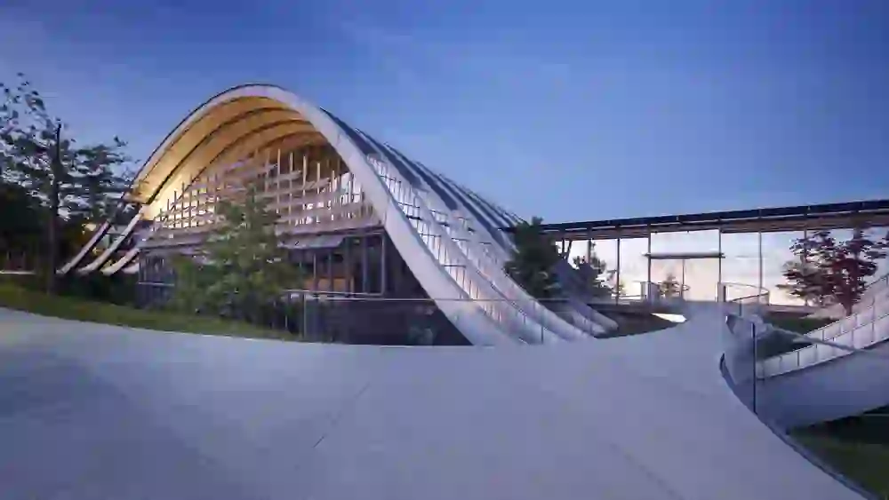 Das Bild zeigt die beeindruckende Aussenansicht des Zentrums Paul Klee in Bern, ein Meisterwerk moderner Architektur. Das Gebäude zeichnet sich durch seine wellenförmigen Formen aus, die sich nahtlos in die umgebende Landschaft einfügen.