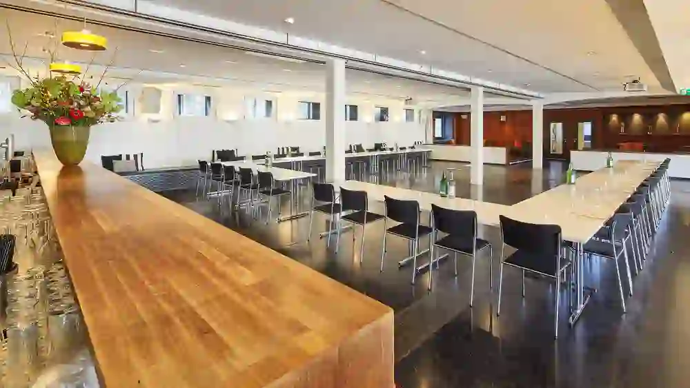 Das Bild zeigt den modernen, hell erleuchteten Veranstaltungsraum der Schwellenmätteli Restaurants mit einem langen Konferenztisch, der zum Gespräch einlädt