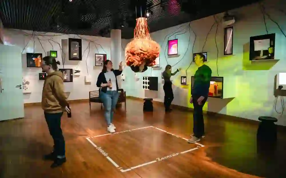 Visitors interactively explore a modern exhibition. The playful, creative atmosphere is palpable as they stroll between the exhibits and unusual installations. Curiosity and pleasure mingle in the space.