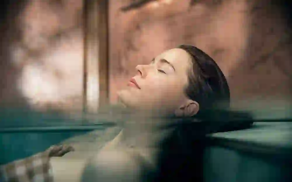 Eine Frau liegt mit geschlossenen Augen entspannt im Wasser, ihr Gesicht friedvoll und entspannt, umgeben von der warmen Atmosphäre des Hammam & Spa Oktogon.