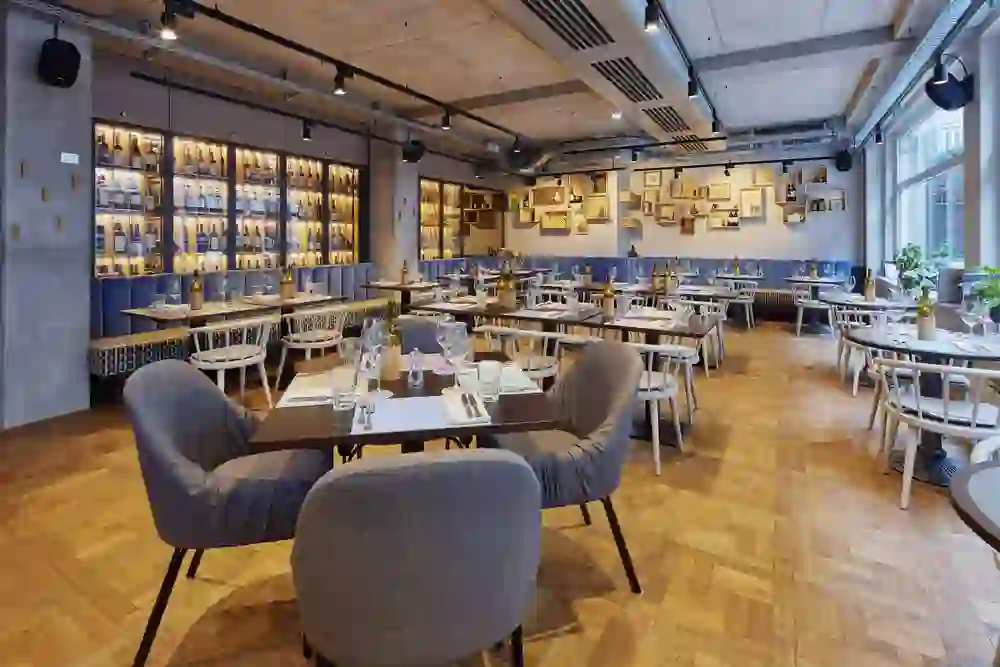 Modernes Restaurant mit beleuchteten Weinregalen und Kunst an den Wänden, ausstrahlend eine kultivierte und gastfreundliche Stimmung.