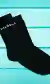 Sur la photo, on voit des chaussettes noires avec l'inscription "VELÖÖLE" en blanc, drapées sur un fond en bois turquoise. La scène respire l'élégance sobre et le style urbain - une déclaration cool pour les fans de vélo.