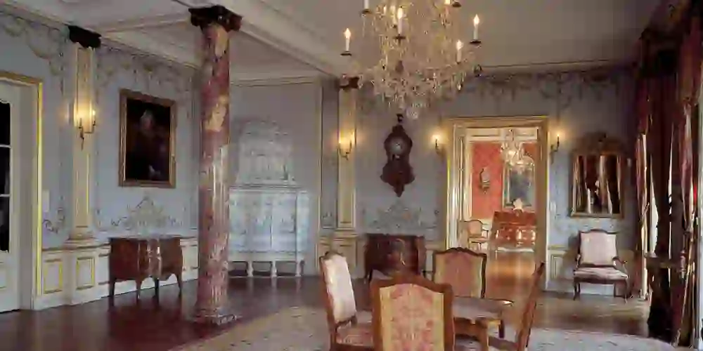 Das Innere des Schlosses Jegenstorf strahlt Eleganz und Pracht aus. Hohe Säulen, glänzende Parkettböden und prächtige Kronleuchter reflektieren das Licht. Jeder Gegenstand, von den vergoldeten Spiegeln bis hin zu den detailreichen Möbelstücken, erzählt Geschichten aus vergangenen Zeiten.