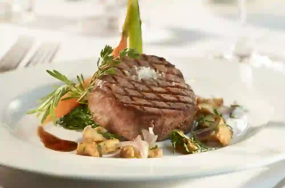 Perfectly cooked steak on an elegant plate, served with fresh herbs, promises an enjoyable flavour experience.