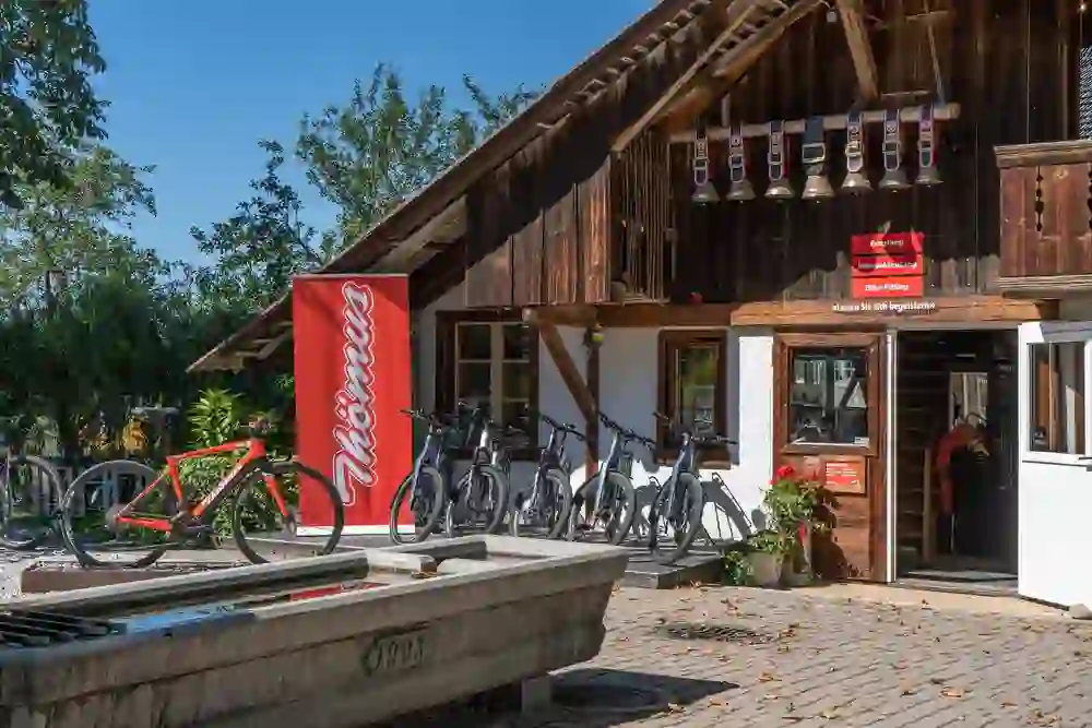 The sun shines in front of the rustic backdrop of the Thömus shop, bikes are waiting for enthusiastic bikers, invited by the warm atmosphere to go on a discovery tour on two wheels in the idyllic surroundings.