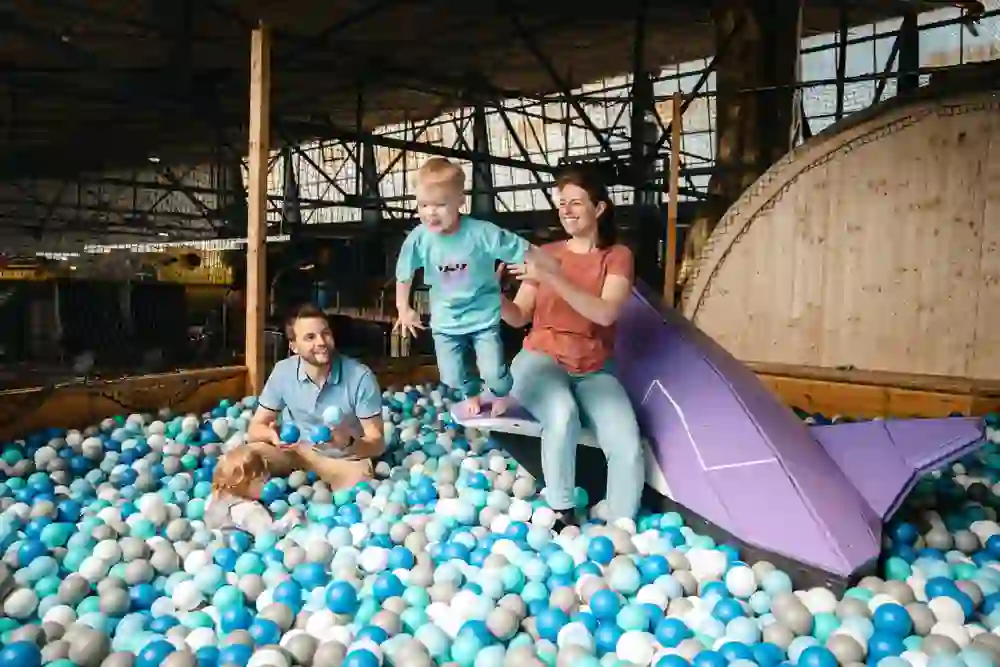 Auf dem Bild ist eine Familien zu sehen welche in einem Bälle-Bad viel Spass hat.