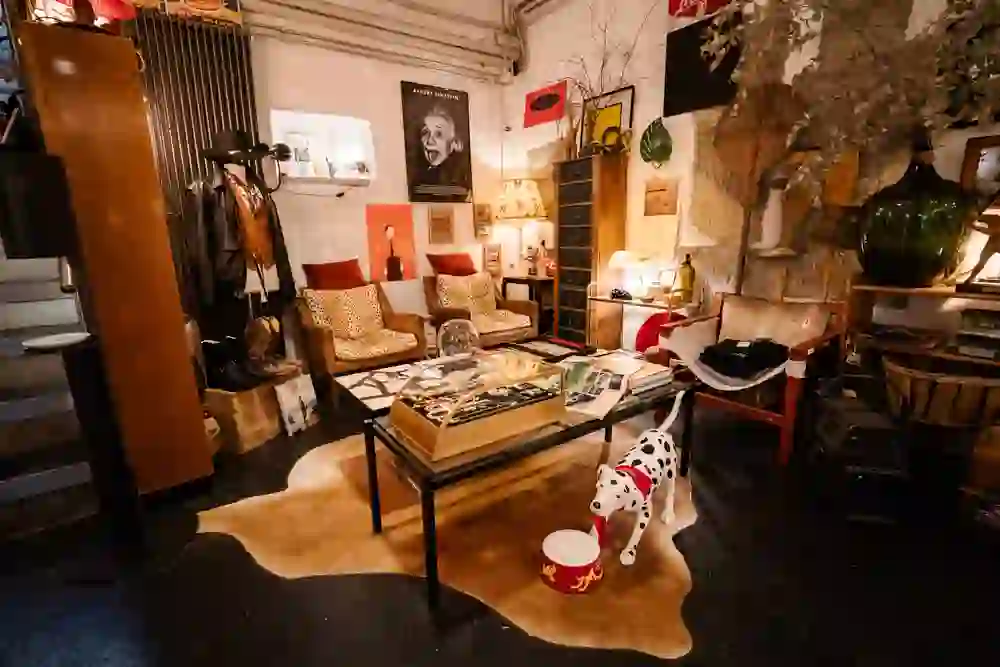 The photo captures an eclectic and artistically designed corner that is part of the vintage shop UndergroundStation. There is a vibrant mix of retro furniture, art on the walls and varied decorative items that together create an inviting, almost homely atmosphere. A Dalmatian figurine adds a playful touch, while the various items take the eye on a journey through the decades.
