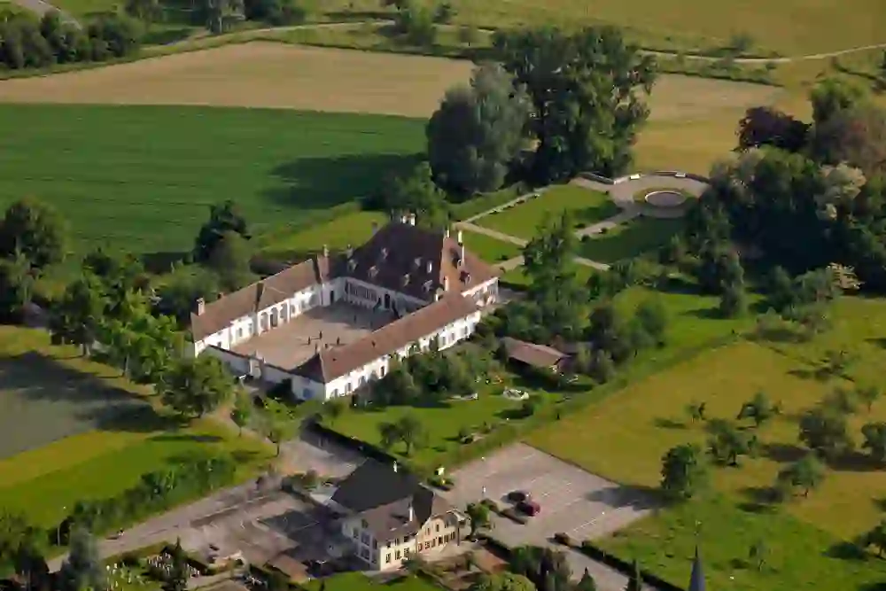 Sur la photo, on peut voir le château de Thunstetten à vol d'oiseau, niché dans les espaces verts luxuriants du paysage environnant. Le vaste domaine, avec sa pelouse bien entretenue et l'architecture épurée du château, s'intègre harmonieusement dans l'environnement naturel.