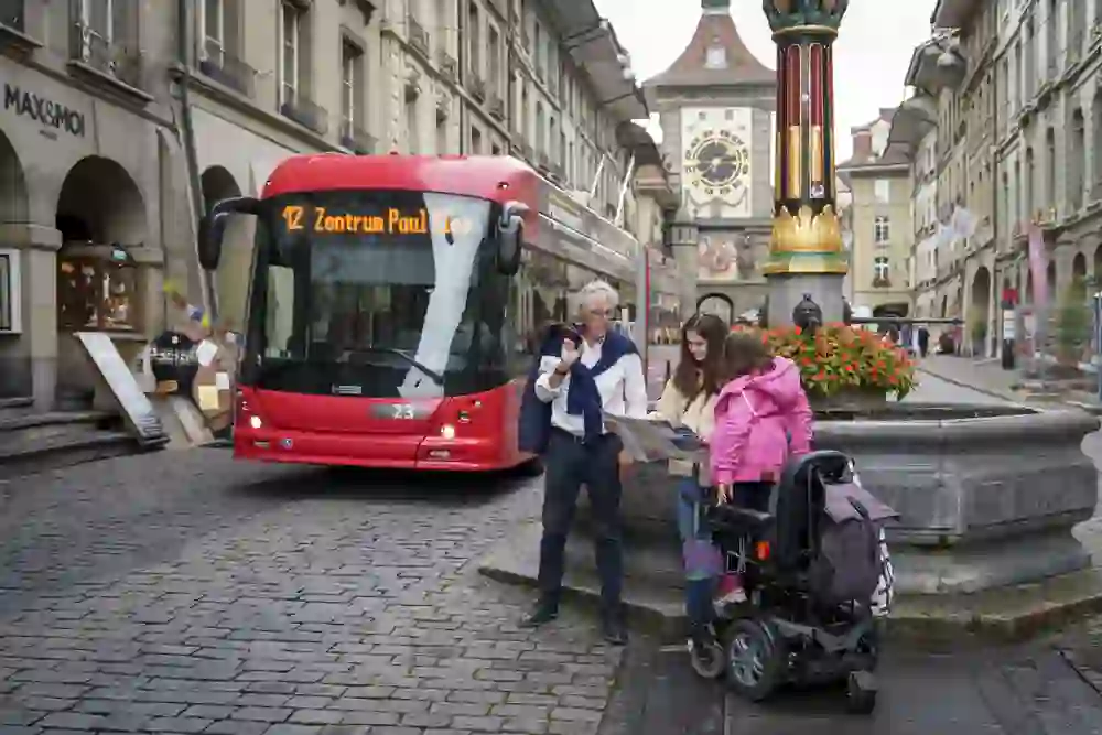 Das Bild zeigt Personen in der Berner Altstadt vor der Zytglogge die eine City Map studieren während ein Bus vorbei fährt
