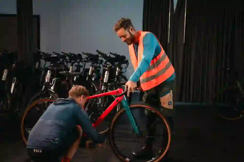 The picture shows two men marvelling at and repairing a bicycle