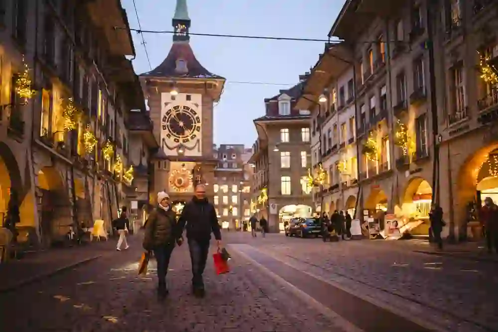 L'immagine mostra una coppia che passeggia per le strade illuminate di Berna e fa i suoi acquisti natalizi.