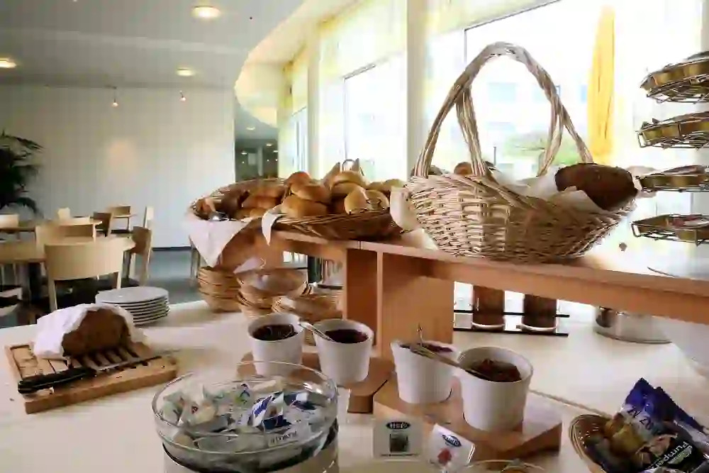 Das Bild zeigt den Frühstücksbereich des Hotel Grauholz in Ittigen, reich bestückt mit frischen Brötchen und Aufstrichen, der eine gemütliche und einladende Stimmung für einen angenehmen Start in den Tag ausstrahlt.