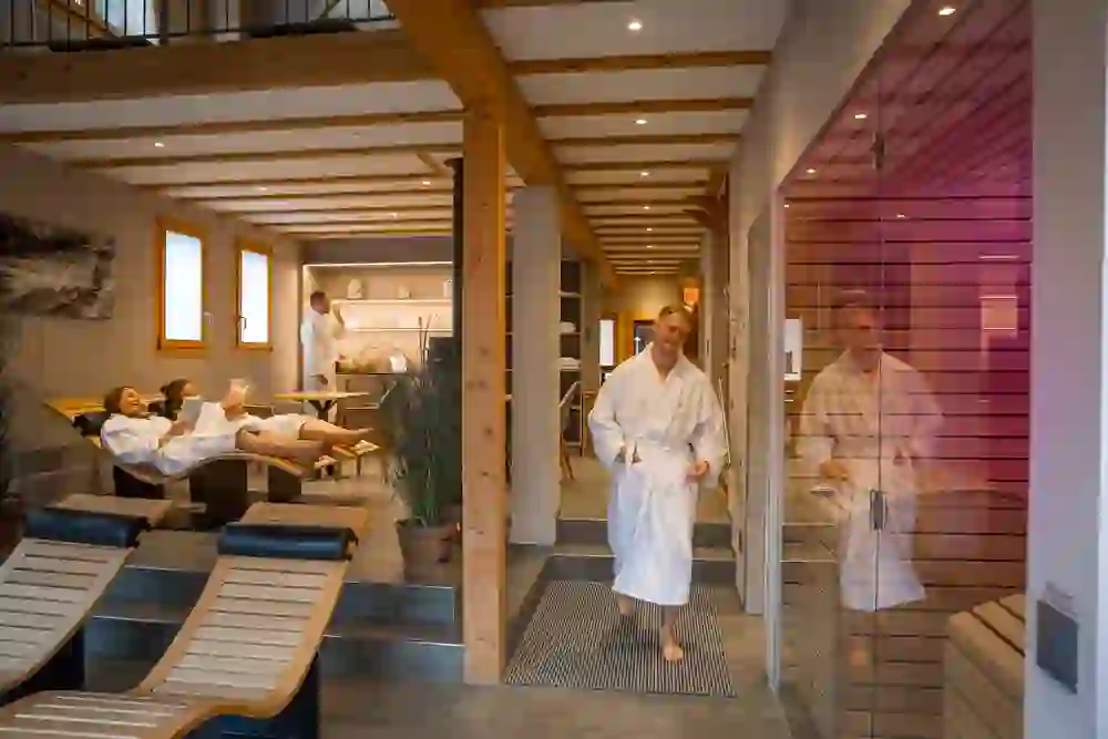 Das Bild zeigt den Wellnessbereich des Romantikhotels Bären Dürrenroth mit Gästen in Bademänteln, die Entspannung in einer ruhigen, warmen Atmosphäre geniessen, umgeben von sanfter Beleuchtung und modernem Komfort.