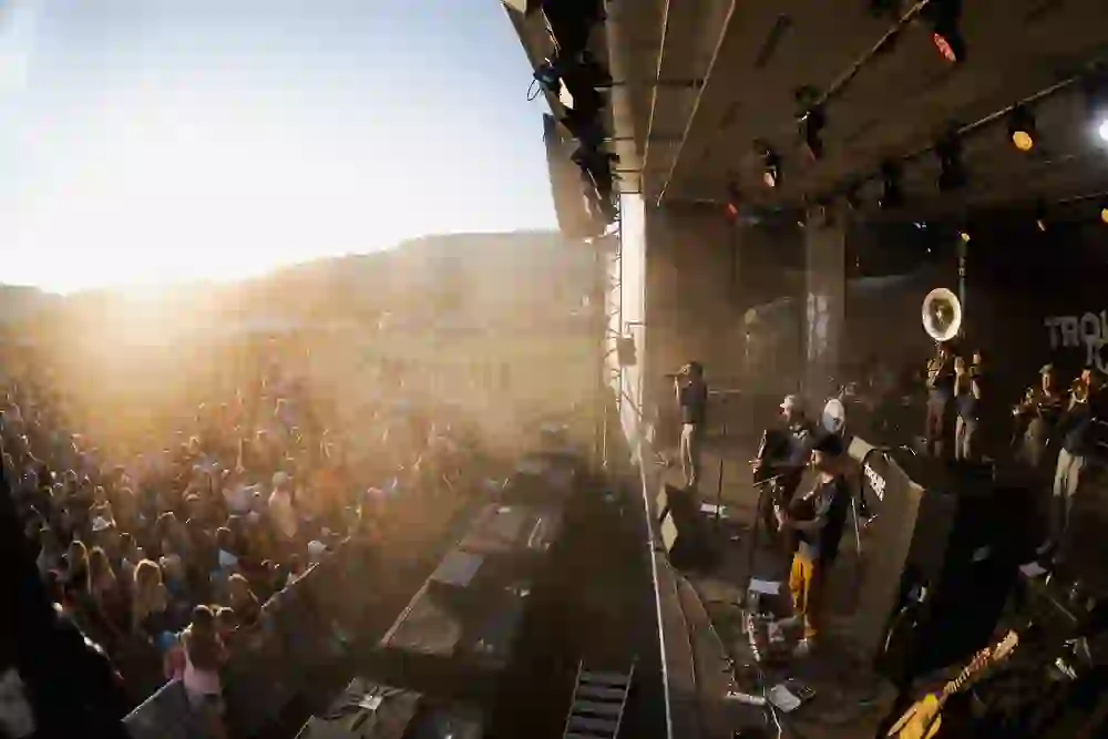 Das Bild zeigt das Stäcketöri Festival in Zäziwil in goldenes Abendlicht getaucht. Die Band spielt voller Energie, die Menge feiert ausgelassen – ein Sommermoment voller Musik, Gemeinschaft und Lebensfreude, der unter die Haut geht.