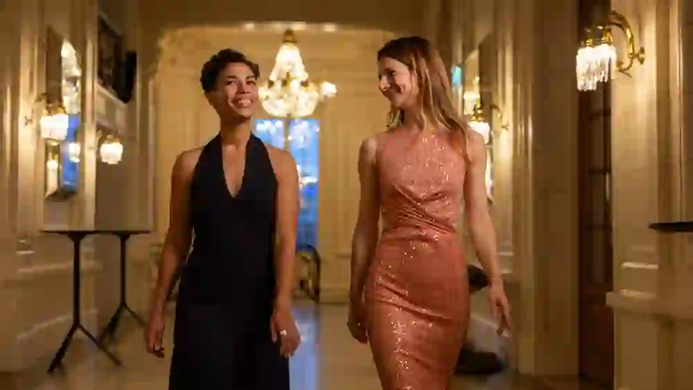 Zwei elegant gekleidete Frauen gehen lachend durch das festlich beleuchtete Foyer eines historischen Theaters in Bern. Kronleuchter, Wandverzierungen und Spiegel schaffen eine edle Atmosphäre – der Moment wirkt stilvoll und entspannt zugleich.