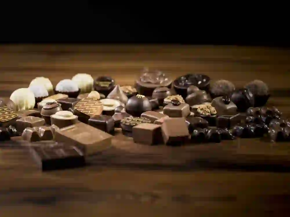 An exquisite selection of chocolates from Confiserie Eichenberger, arranged on dark wood, promises sweet delights and a touch of luxury that would enchant any gourmet.