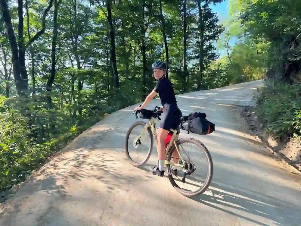 The picture shows a young woman who has rented a Garvelbike from City Cycles and is riding in the beautiful countryside